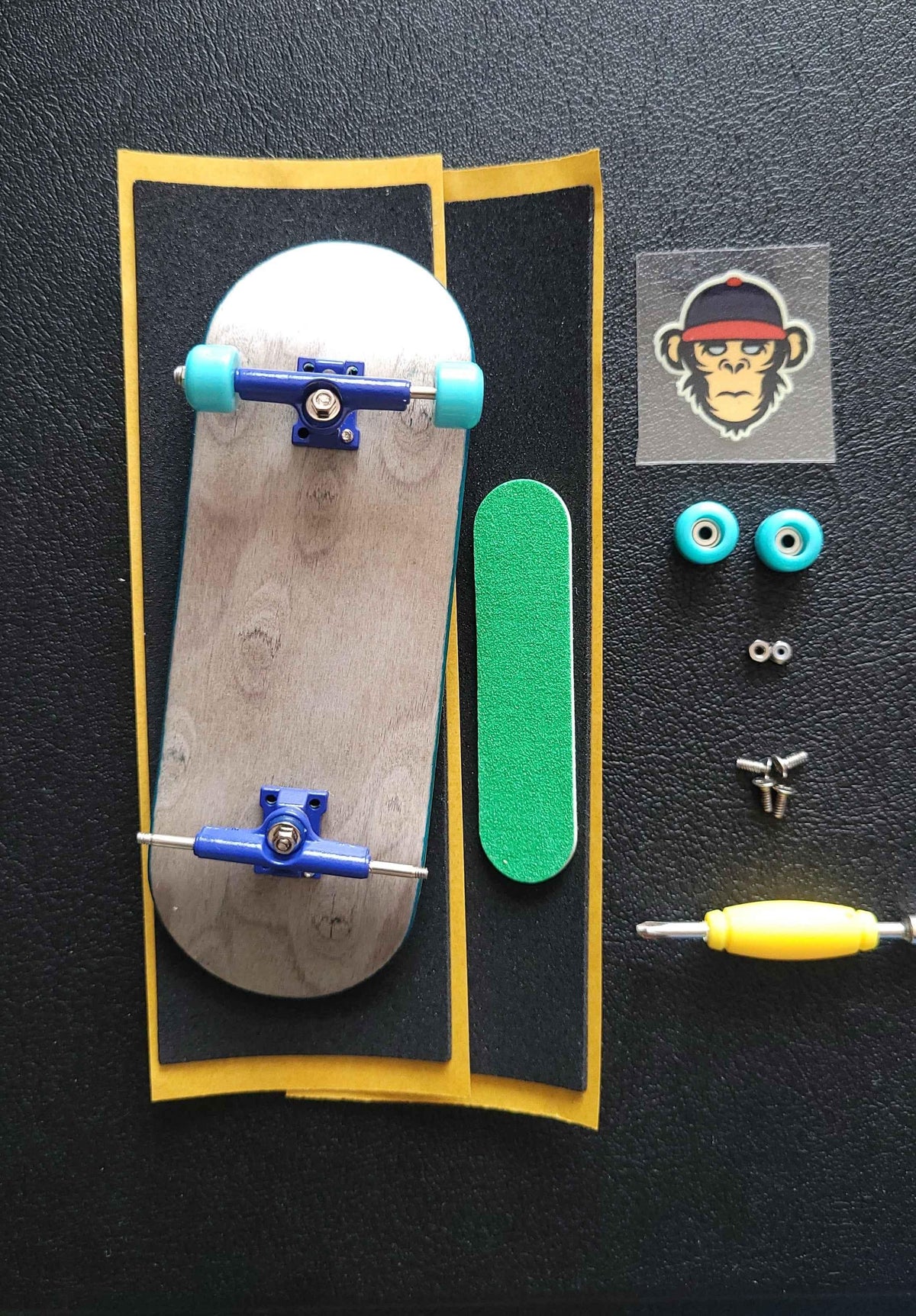 Custom fingerboard kit with wooden deck, blue trucks, teal wheels, and accessories.