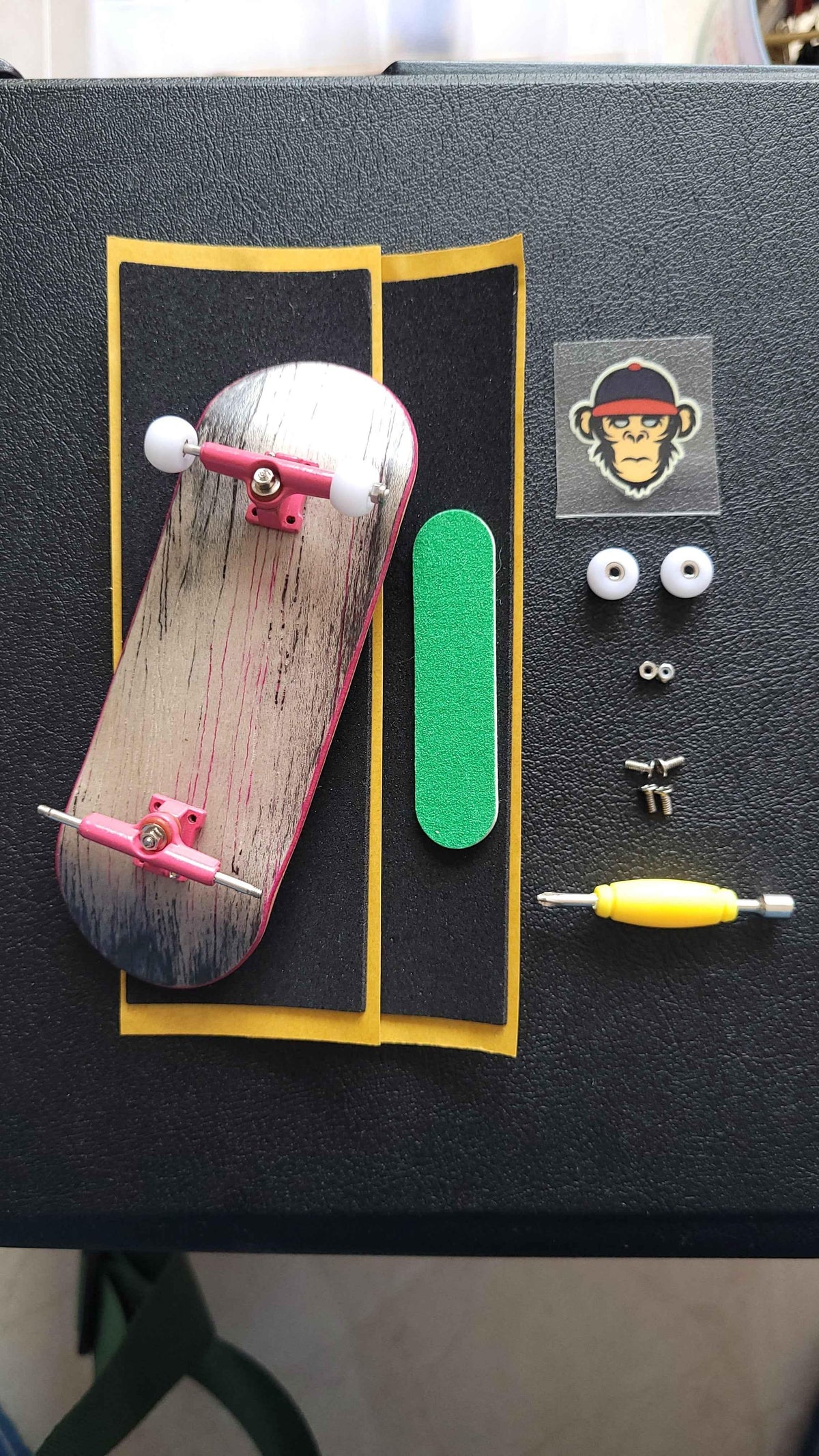 Custom fingerboard kit with deck, pink trucks, white wheels, and green grip tape.