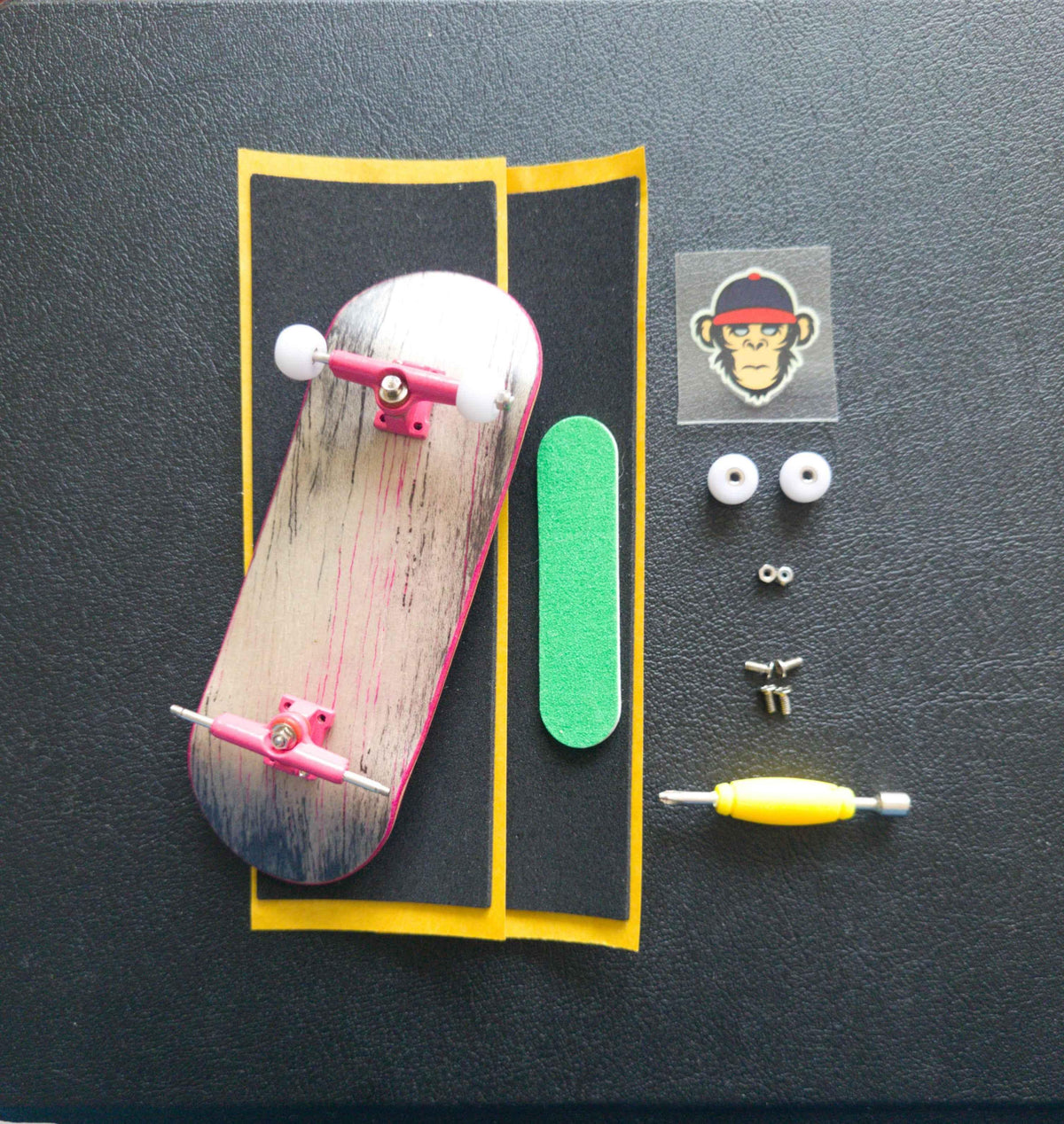 Custom fingerboard kit with painted deck, pink trucks, white wheels, and grip tape.