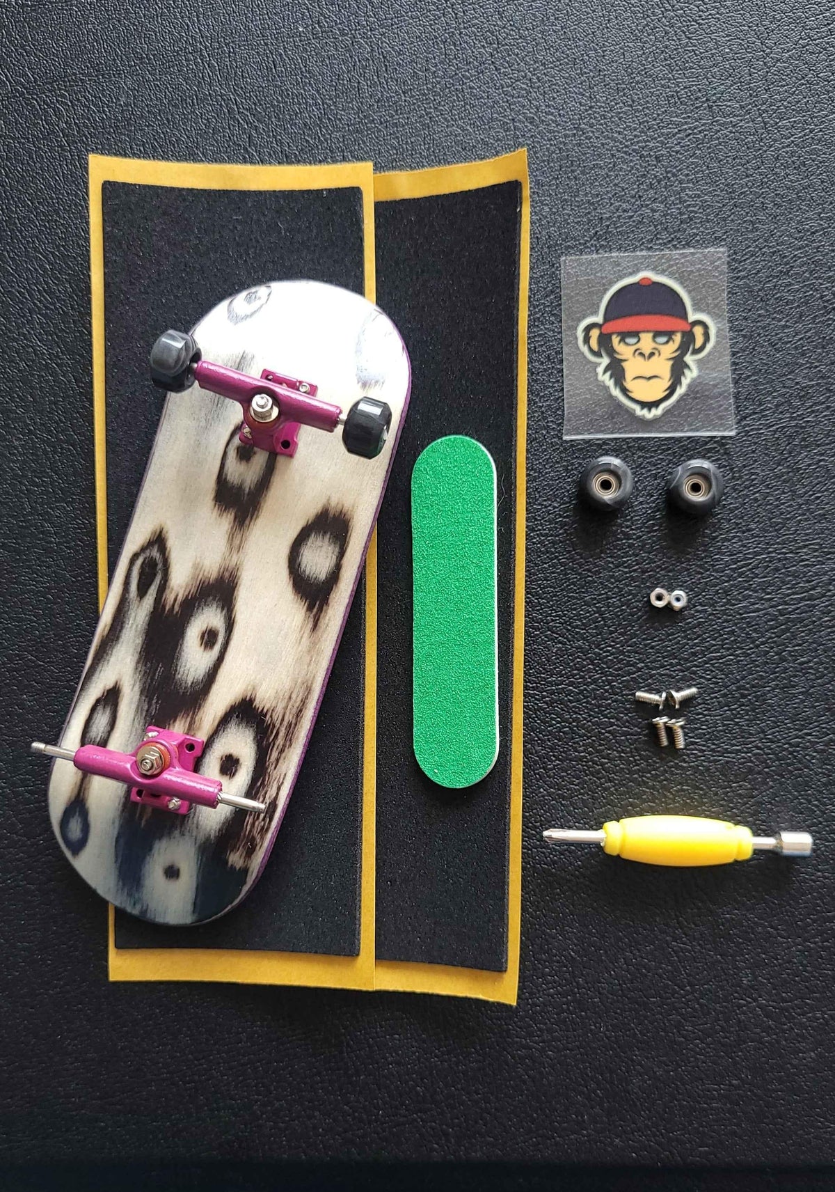 Custom fingerboard kit with printed deck, purple trucks, wheels, and accessories.