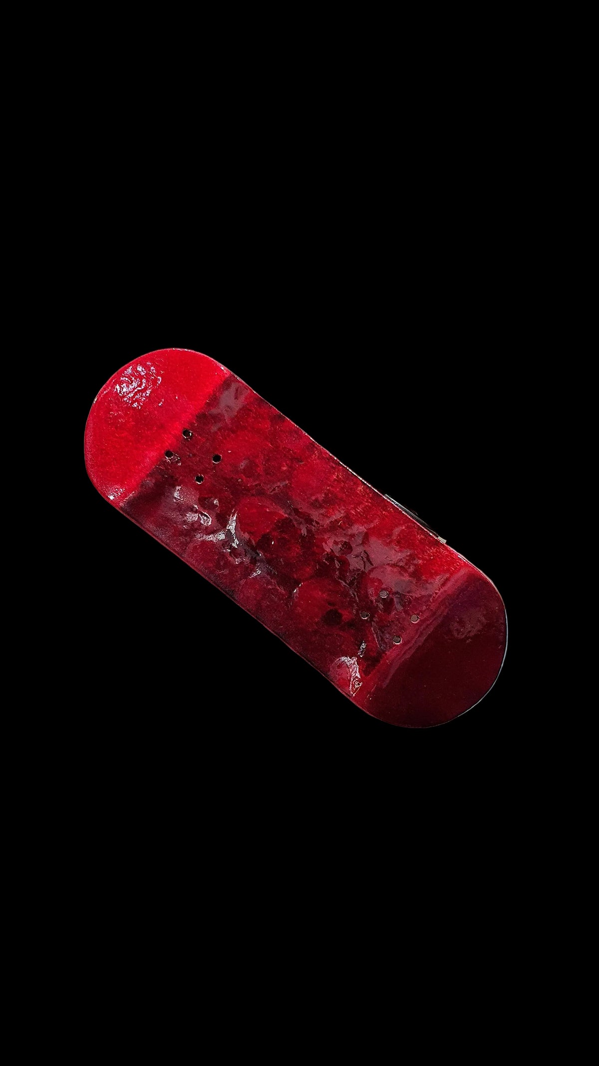 Red fingerboard deck diagonal view, glossy weathered texture and mounting holes.