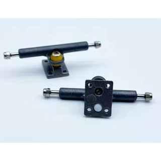 Two sets of professional black fingerboard trucks with gold bushings on a white background