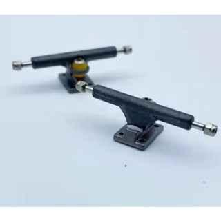 Two professional fingerboard trucks with yellow bushings on a white background