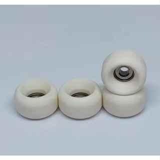 Set of four white miniature fingerboard wheels on a light gray background.