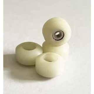 Four white miniature fingerboard wheels with metal bearings on a plain background.