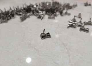 Small metal fingerboard hardware components scattered on a white surface