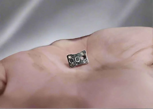 Small metal fingerboard truck component held in a person's hand.