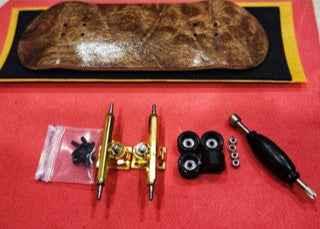 Custom fingerboard kit with wooden deck, gold trucks, black wheels, and tool