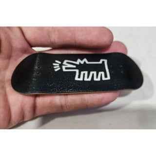 Black custom fingerboard deck with white graphic design held in hand