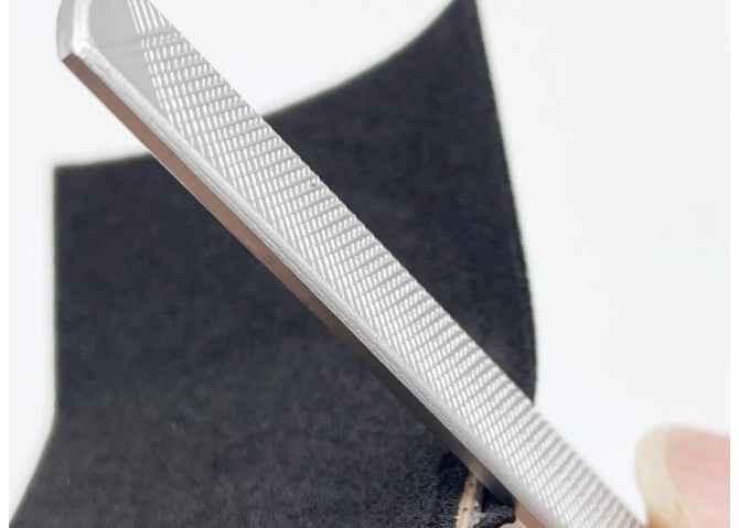 Close-up of a metal file being used on a custom fingerboard deck.
