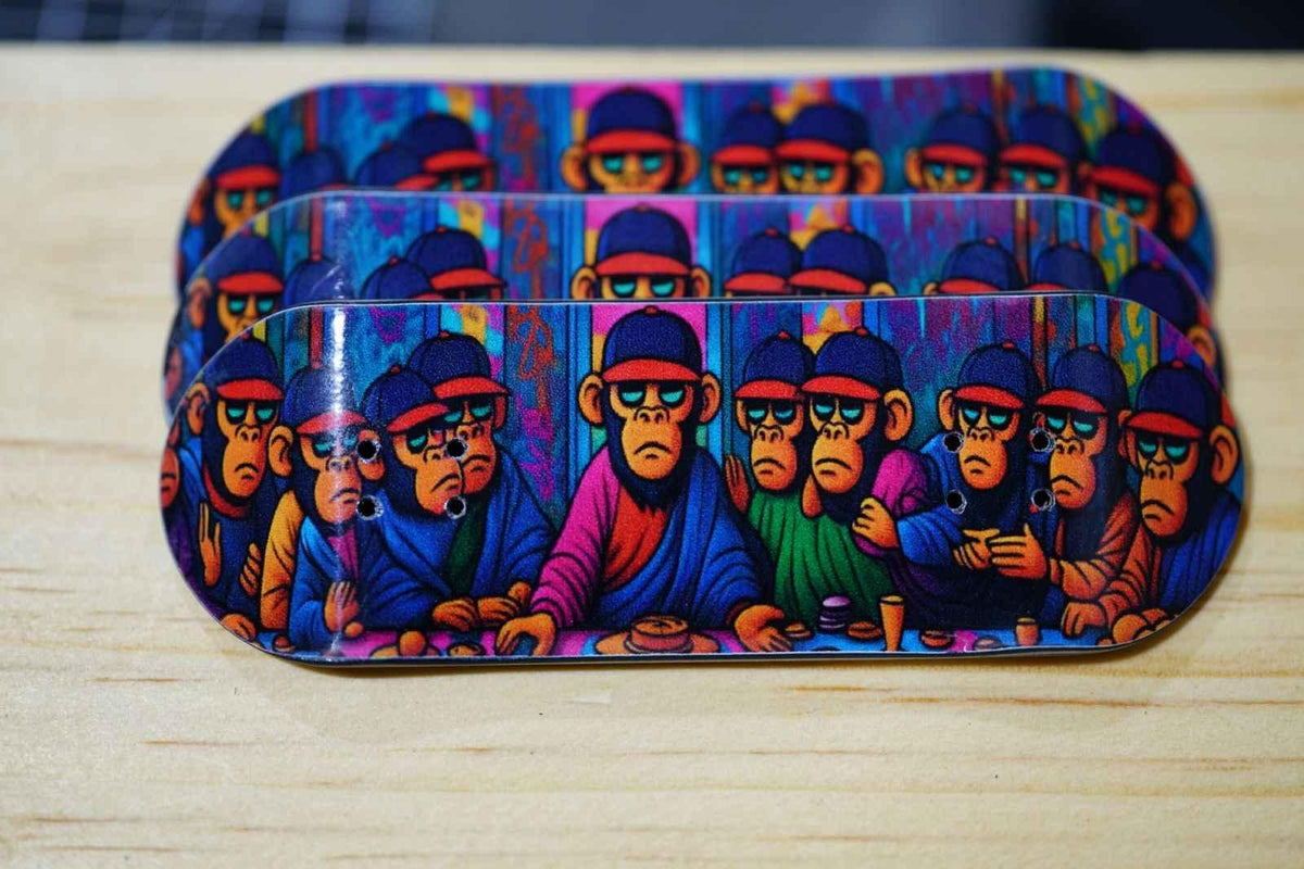 Three custom fingerboard decks featuring colorful monkey character artwork