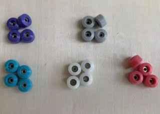 Assorted colorful miniature fingerboard wheels in purple, blue, white, and pink.