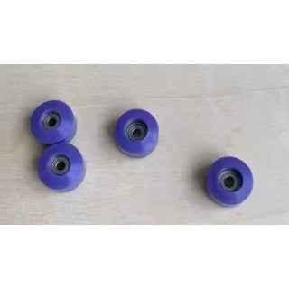 Four small purple fingerboard wheels on a light wood surface.
