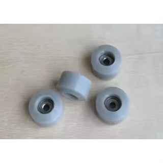 Four small white fingerboard wheels on a light wooden surface.