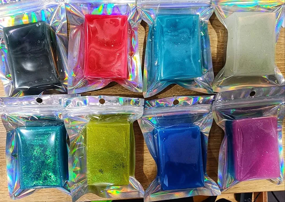 Assorted colorful glittery fingerboard wheels in iridescent holographic packaging.