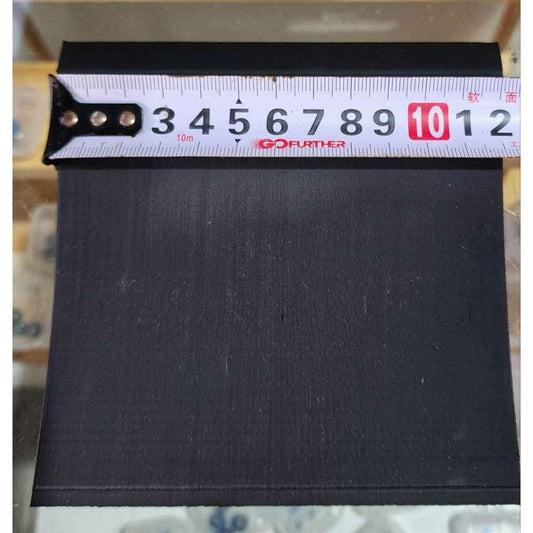 Black fingerboard deck material being measured with a tape measure.