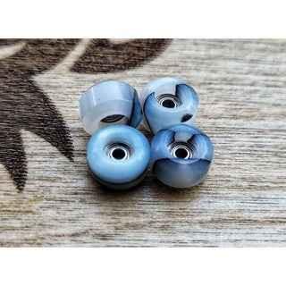 Four translucent blue fingerboard wheels on a wooden surface.