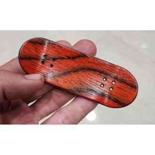 Handmade custom fingerboard deck with red and black wood grain pattern.