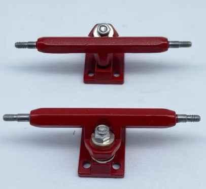 Two red miniature fingerboard trucks with silver hardware on a white background