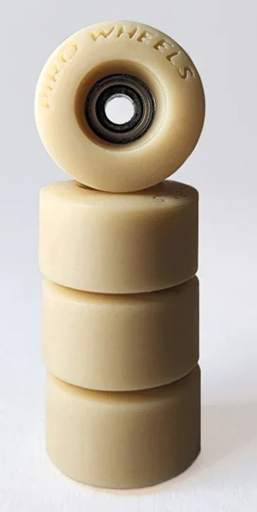 Four cream-colored fingerboard wheels stacked vertically with one wheel on top showing bearing.