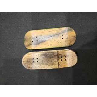 Two handmade wooden fingerboard decks with natural grain patterns on a black background.