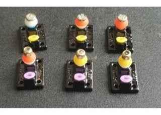 Six colorful custom fingerboard trucks in various colors on a grey surface