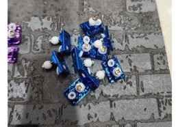 Blue metallic fingerboard trucks and accessories on a grey brick pattern surface