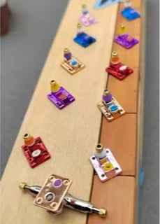 Colorful custom fingerboard trucks displayed on a wooden board