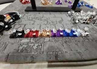 Colorful assortment of fingerboard trucks and hardware on a grey textured surface