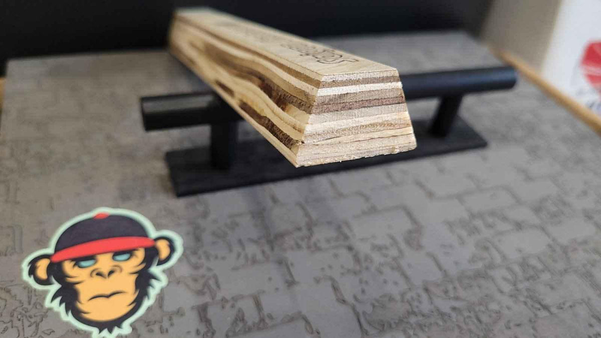 Close-up of a handmade wooden fingerboard deck on a black display stand