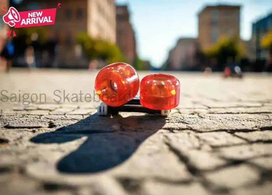 Close-up of red fingerboard wheels on a cobblestone street with blurred city background.