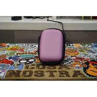 Purple hardshell carrying case on a colorful skateboard sticker collage surface