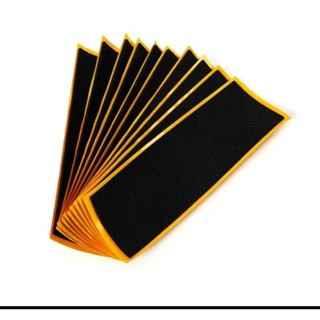 Fan-shaped stack of black grip tape sheets with gold borders for fingerboards