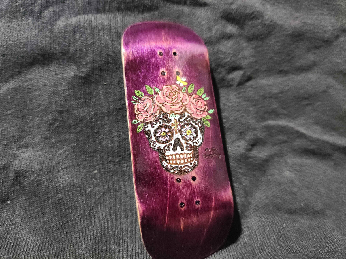 Custom purple fingerboard deck featuring a sugar skull and pink rose graphic.