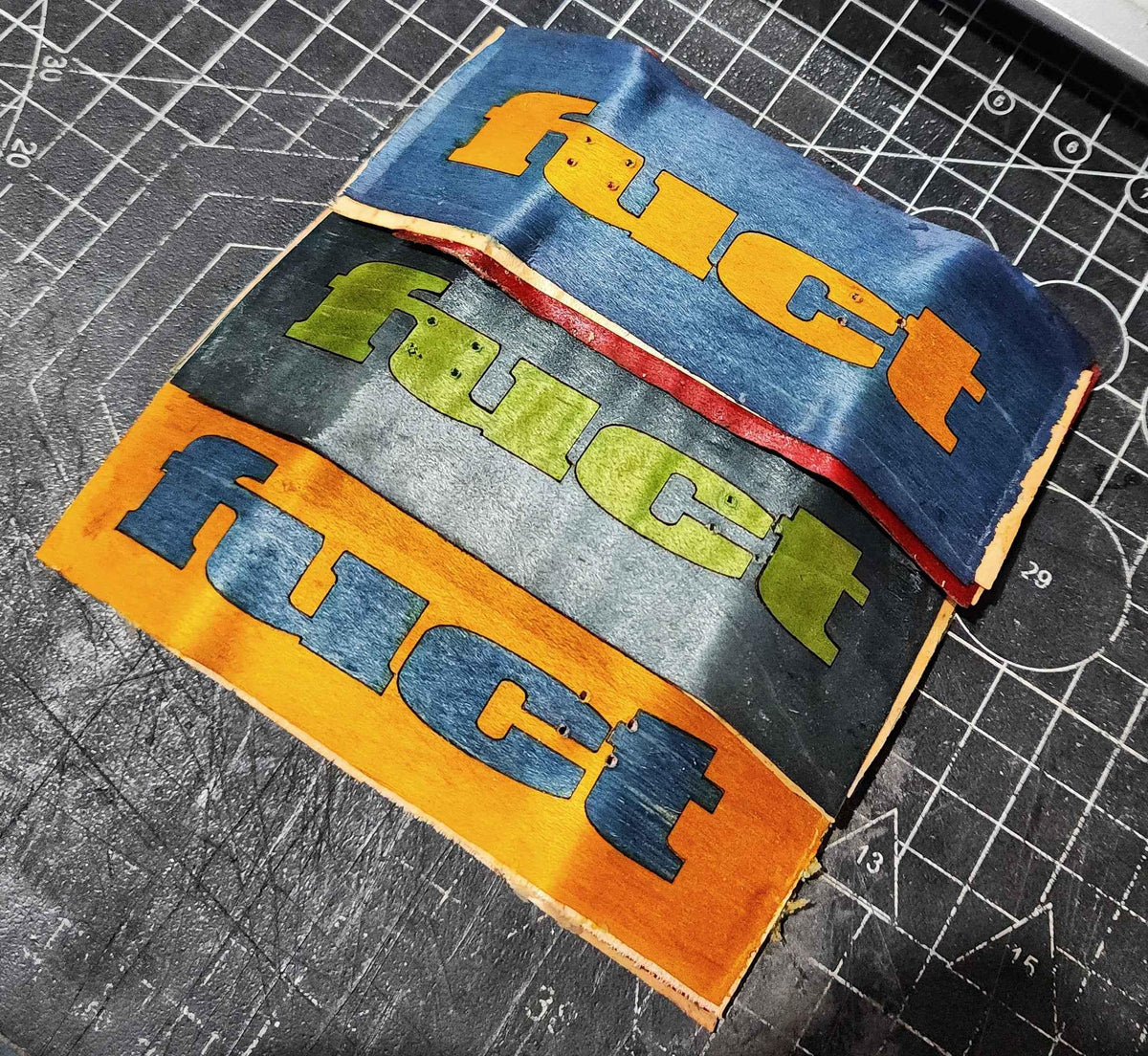 Custom printed fingerboard deck graphics featuring colorful bold typography on a cutting mat.