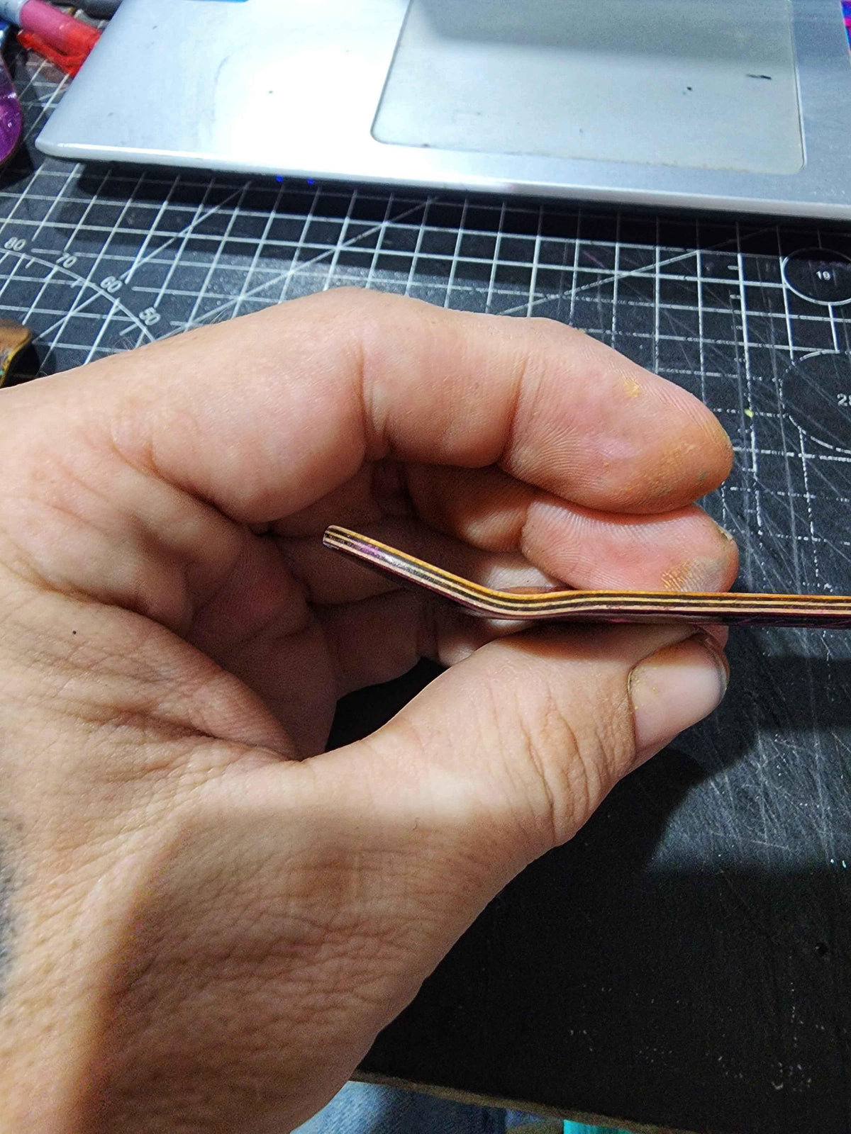 Hand holding a custom metal fingerboard truck component during manufacturing.