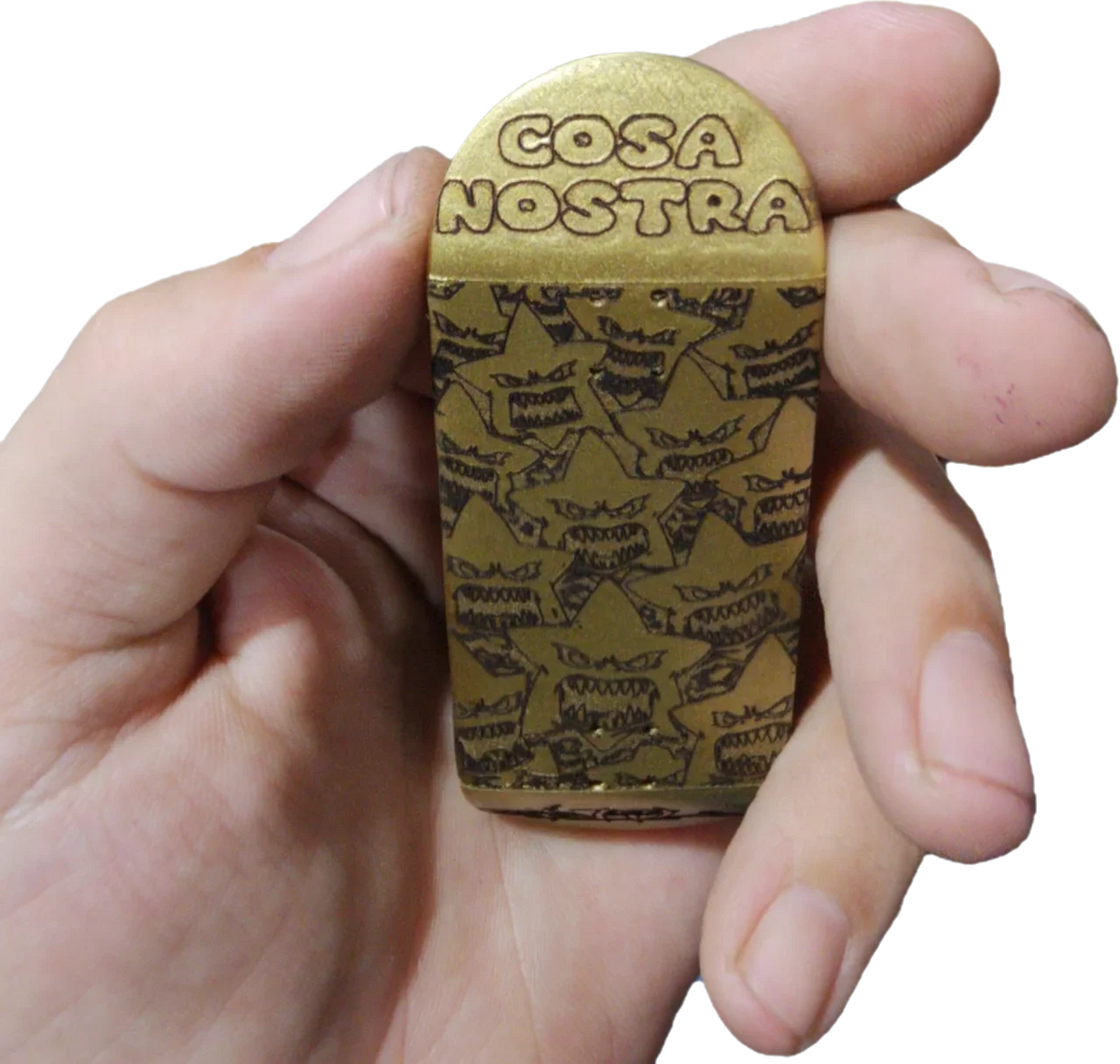 Hand holding a gold fingerboard accessory engraved with Cosa Nostra and monster patterns