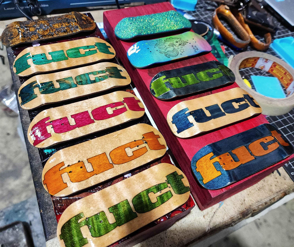 Handmade custom fingerboard decks with colorful graphics on a workbench