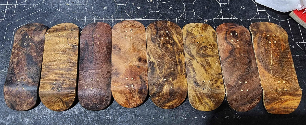 Collection of handmade custom wooden fingerboard decks with various natural wood grains.