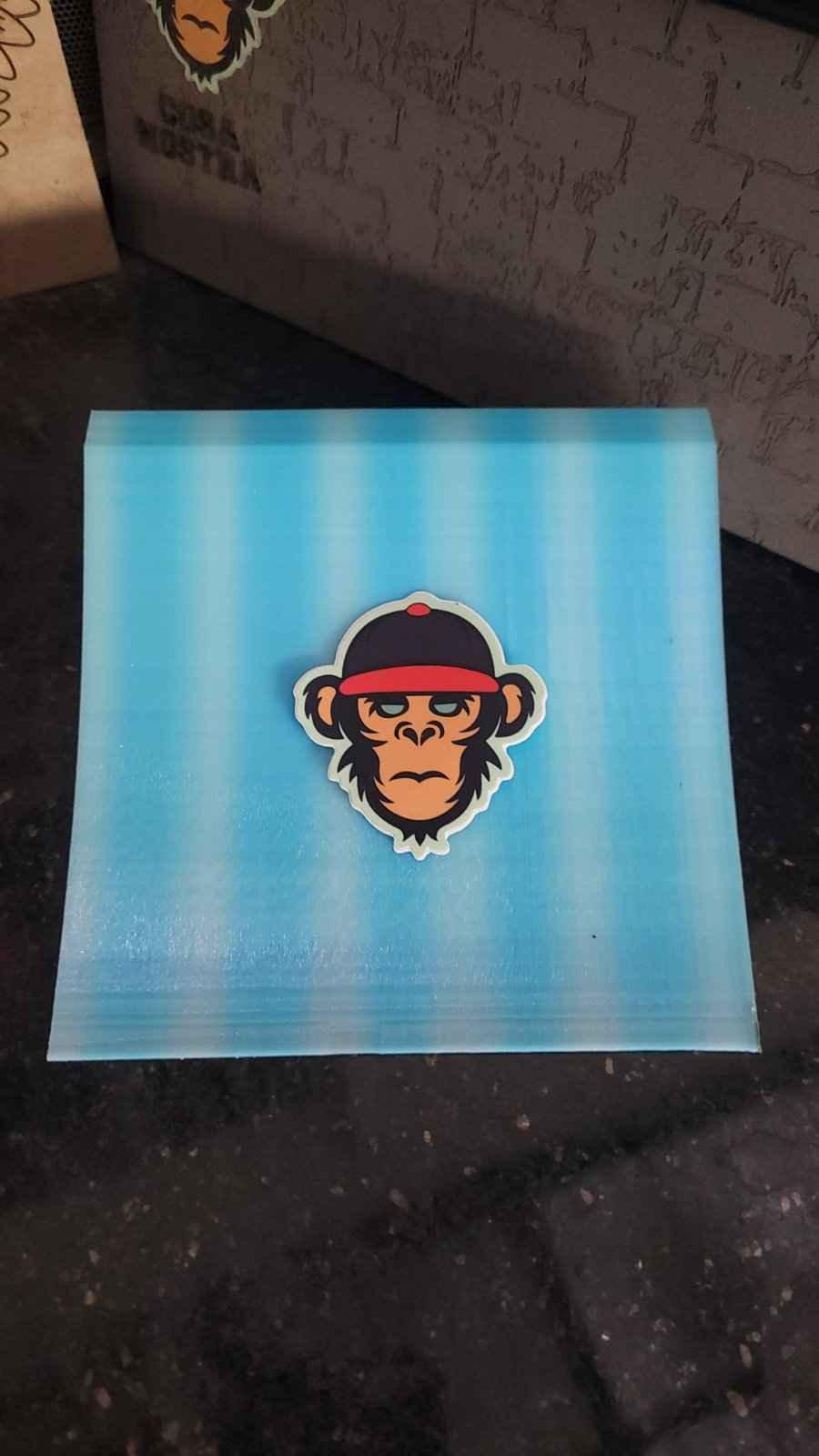 Monkey head sticker wearing a red cap on a blue striped background