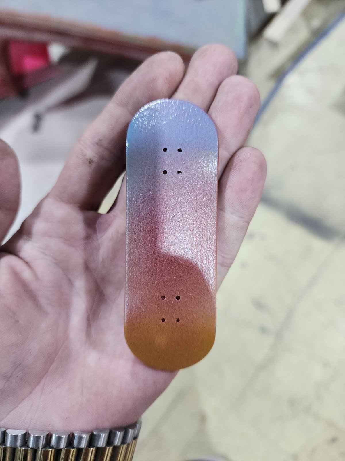Handmade custom fingerboard deck with a blue to orange gradient finish.