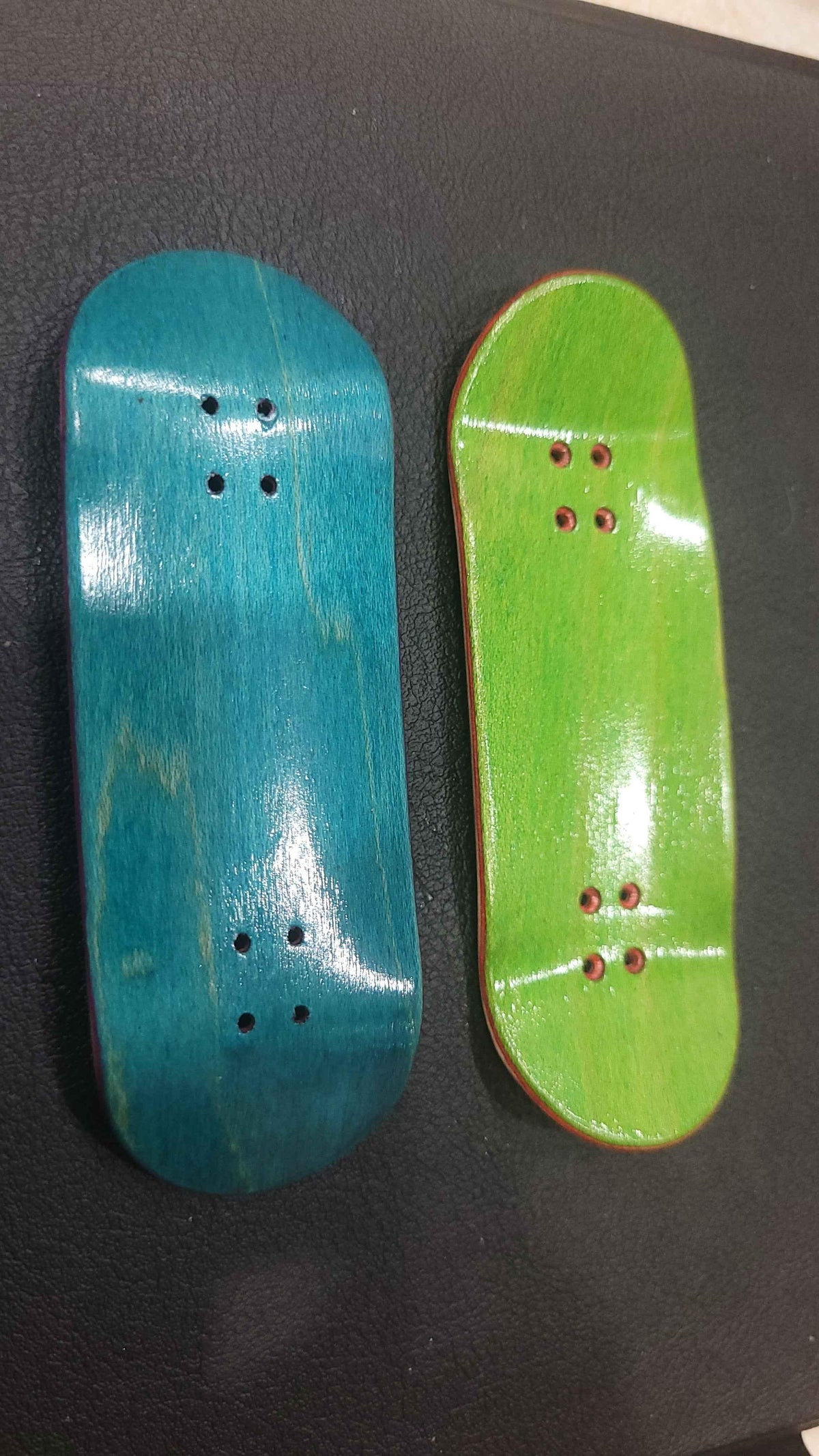 Two handmade custom fingerboard decks in teal and lime green colors.
