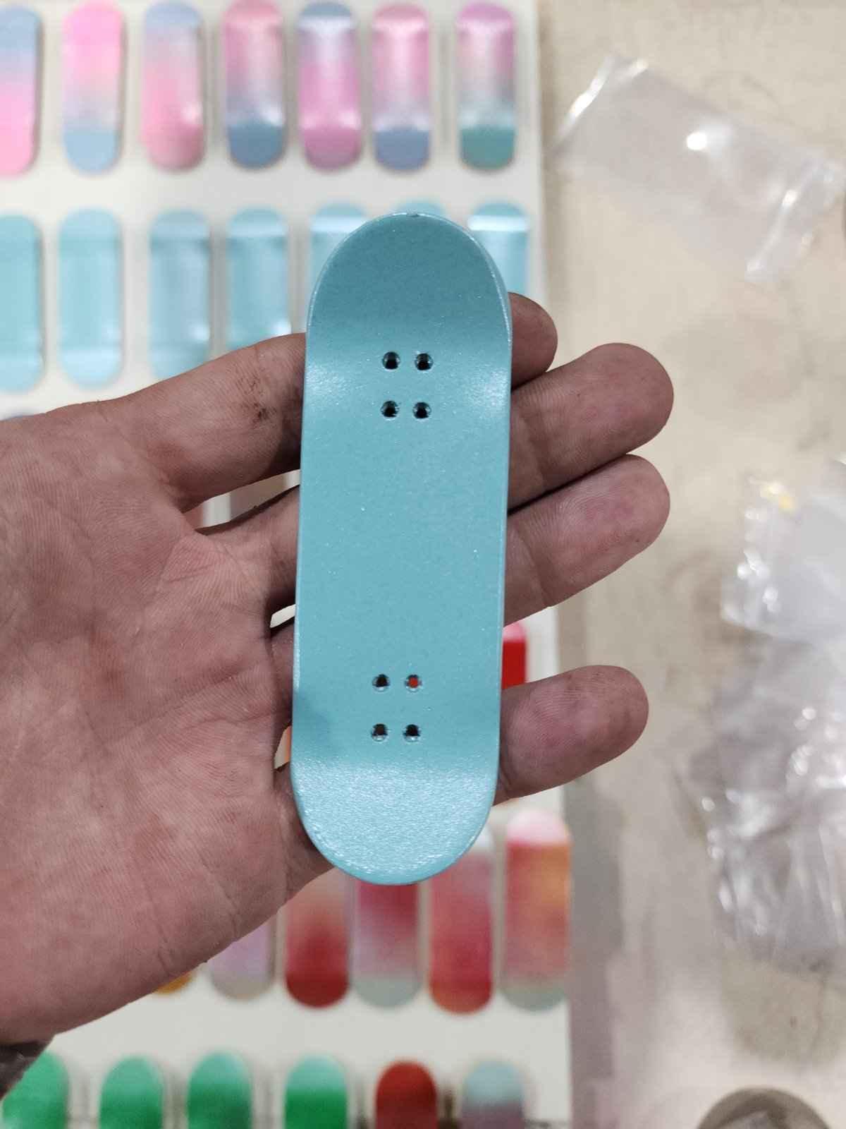 Hand holding a light blue handmade custom fingerboard deck.