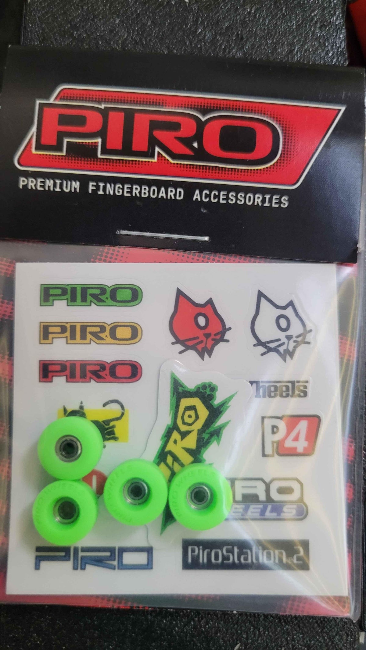 Piro brand fingerboard accessory kit with neon green wheels and various stickers.