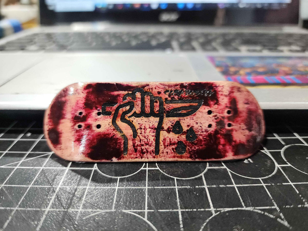 Custom fingerboard deck with a red blood-splatter effect and black graphic illustration.