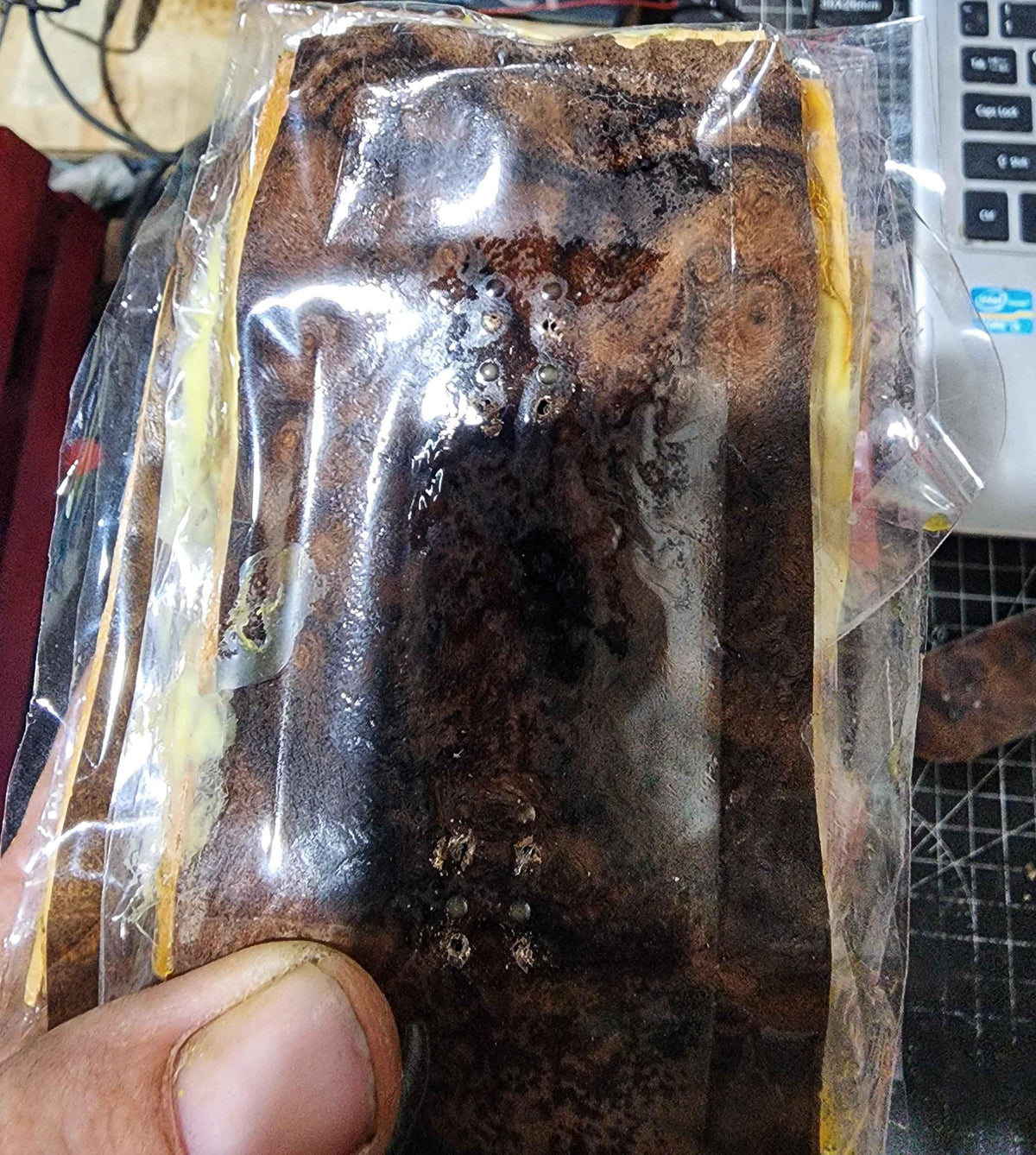 Handmade custom wooden fingerboard deck in protective plastic packaging.