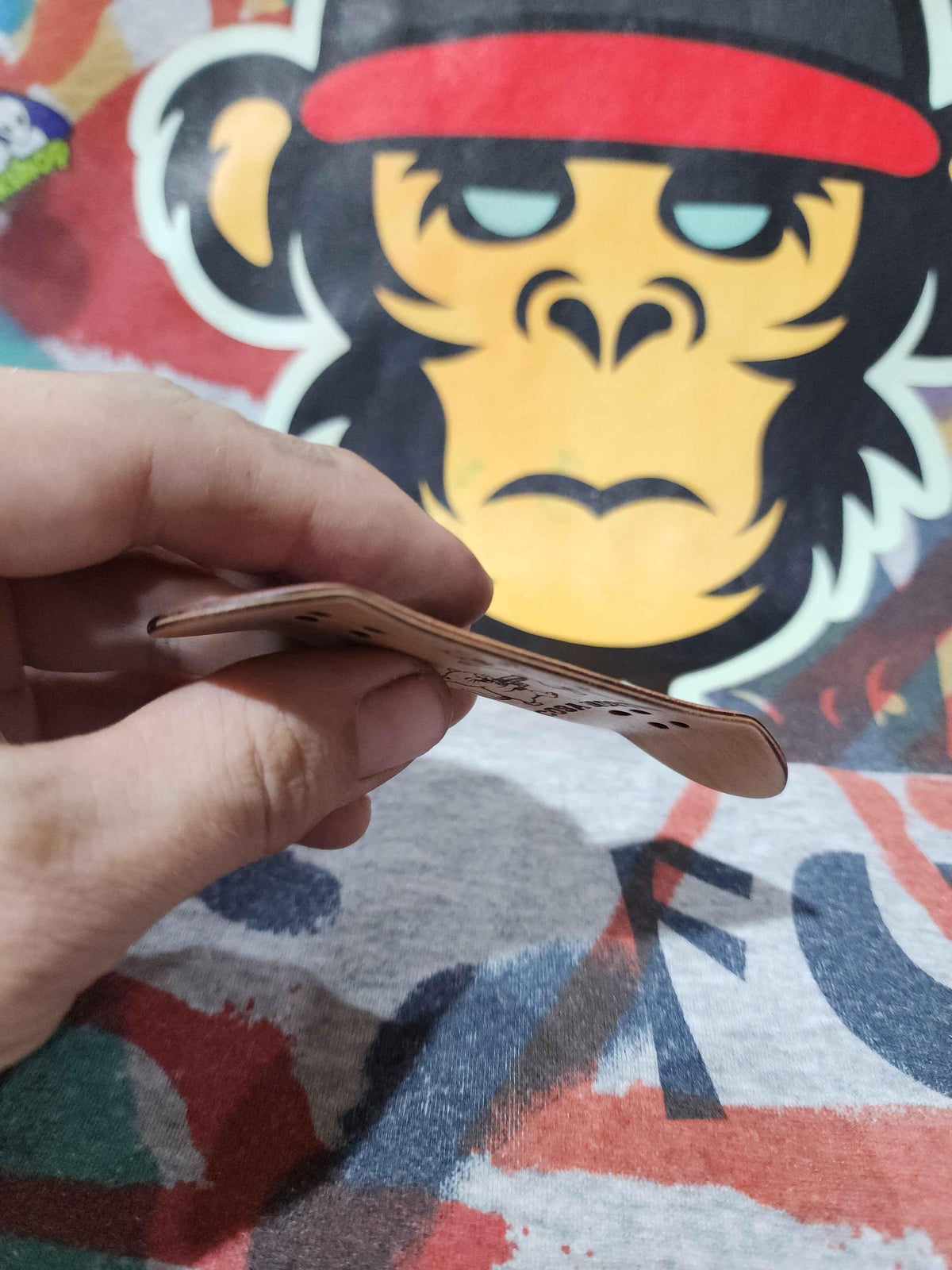 Hand holding a handmade wooden custom fingerboard deck