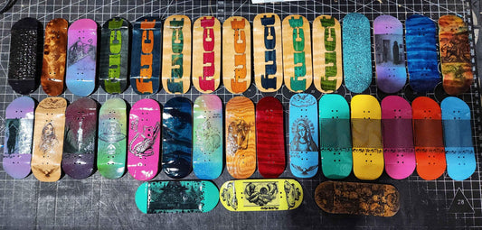 A diverse collection of colorful custom handmade fingerboard decks with various art and graphics.