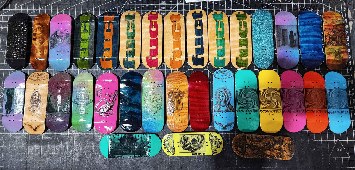 A diverse collection of colorful custom handmade fingerboard decks with various art and graphics.