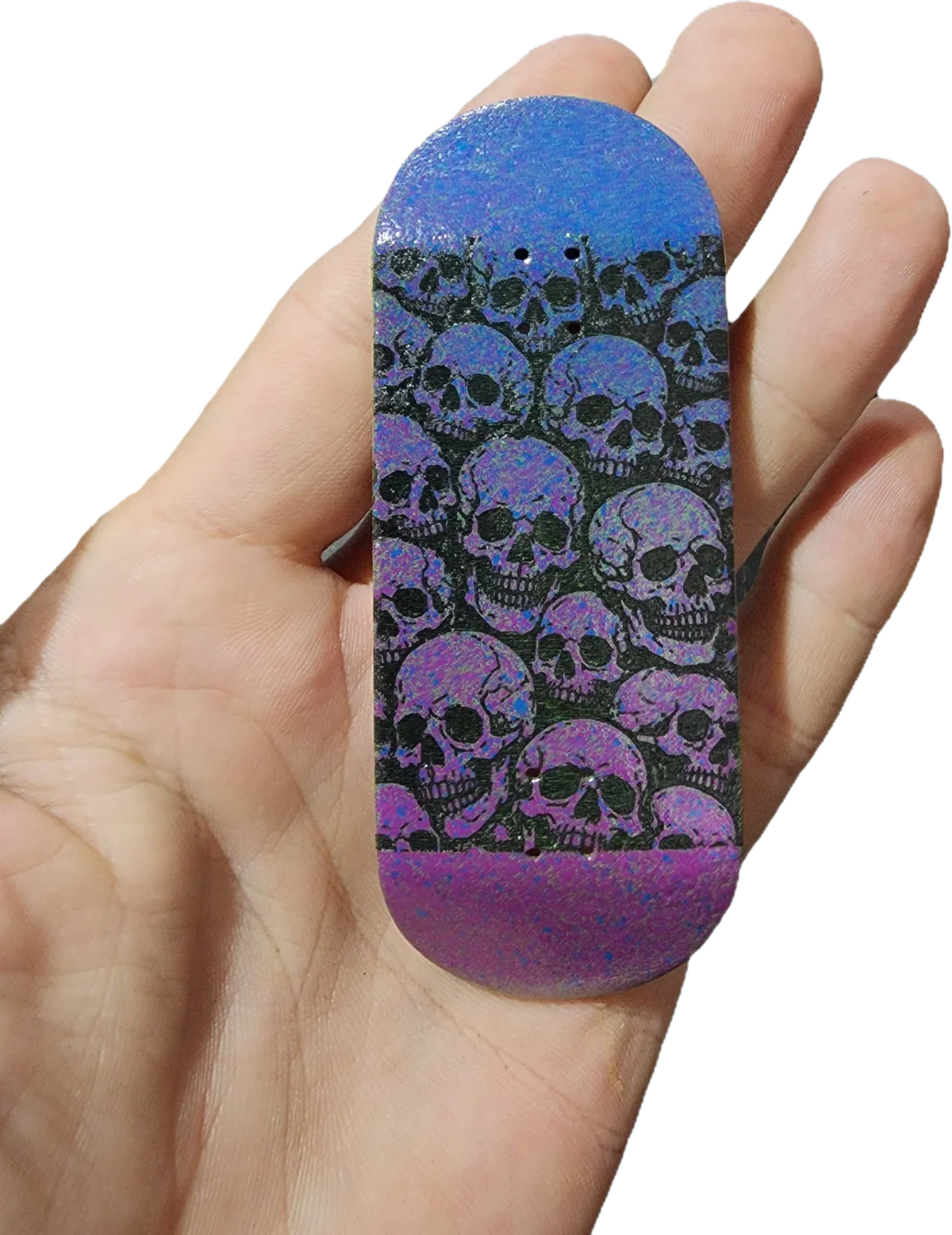 Hand holding a custom fingerboard deck with a purple and blue skull pattern graphic.
